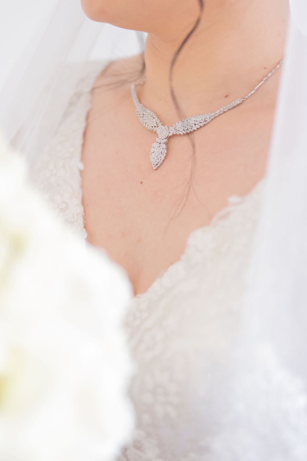 Delicate crystal necklace with wing-like design photographed against white lace and tulle.