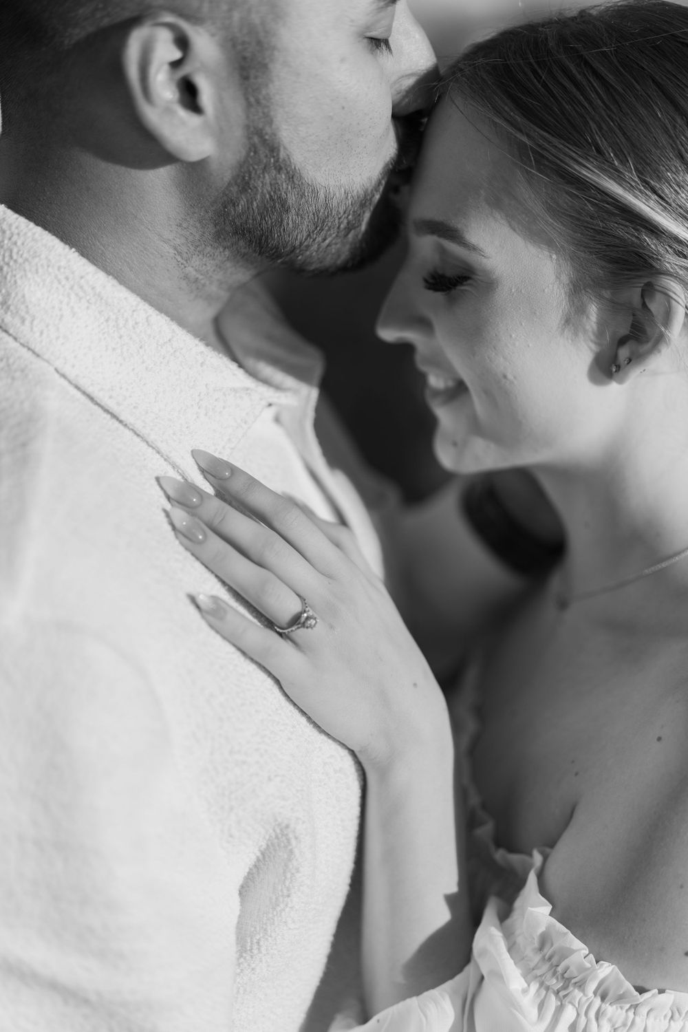 A close-up black and white portrait of a couple sharing a tender moment.