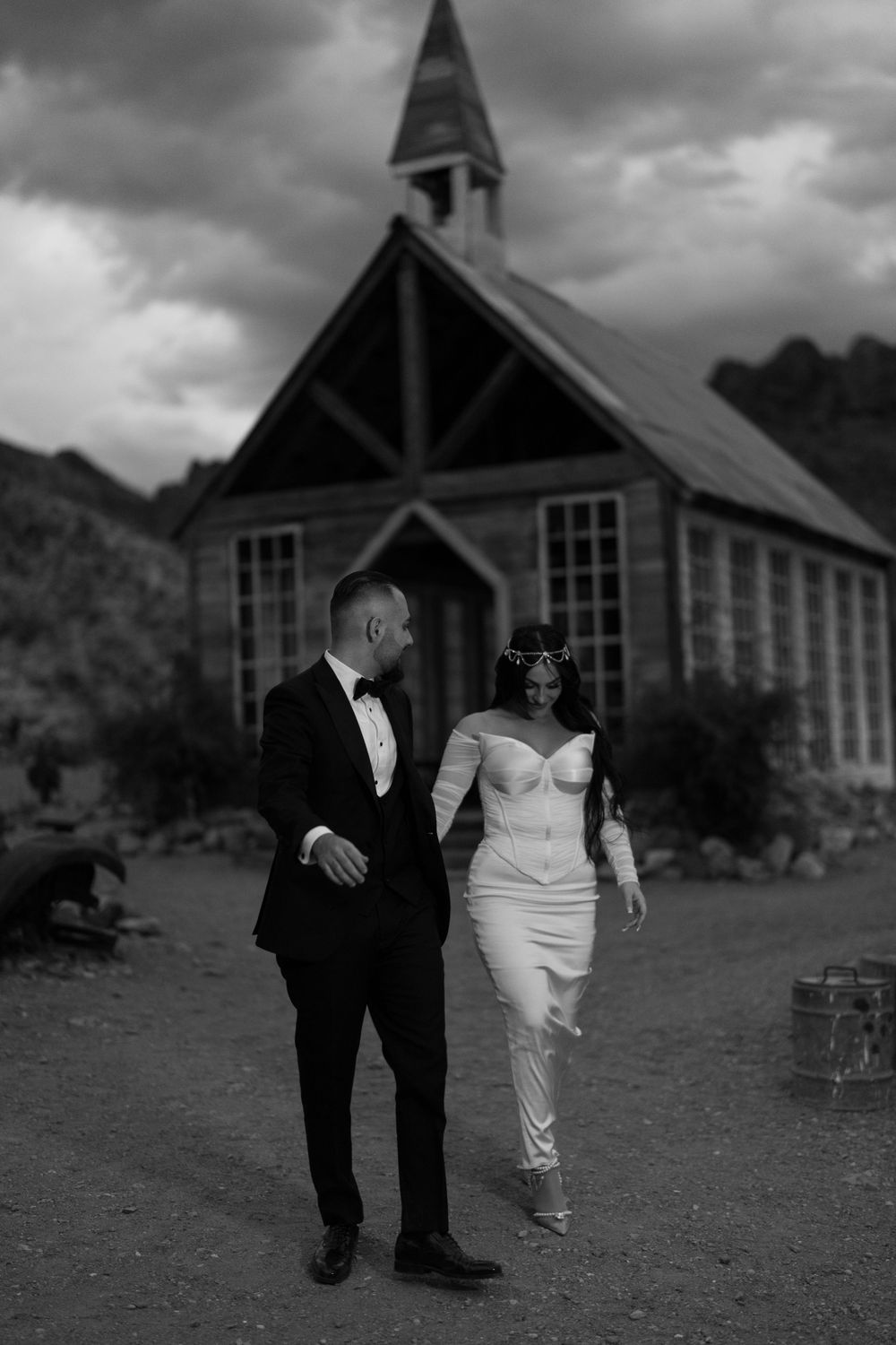 Black and white photo of a couple outside a vintage desert chapel.