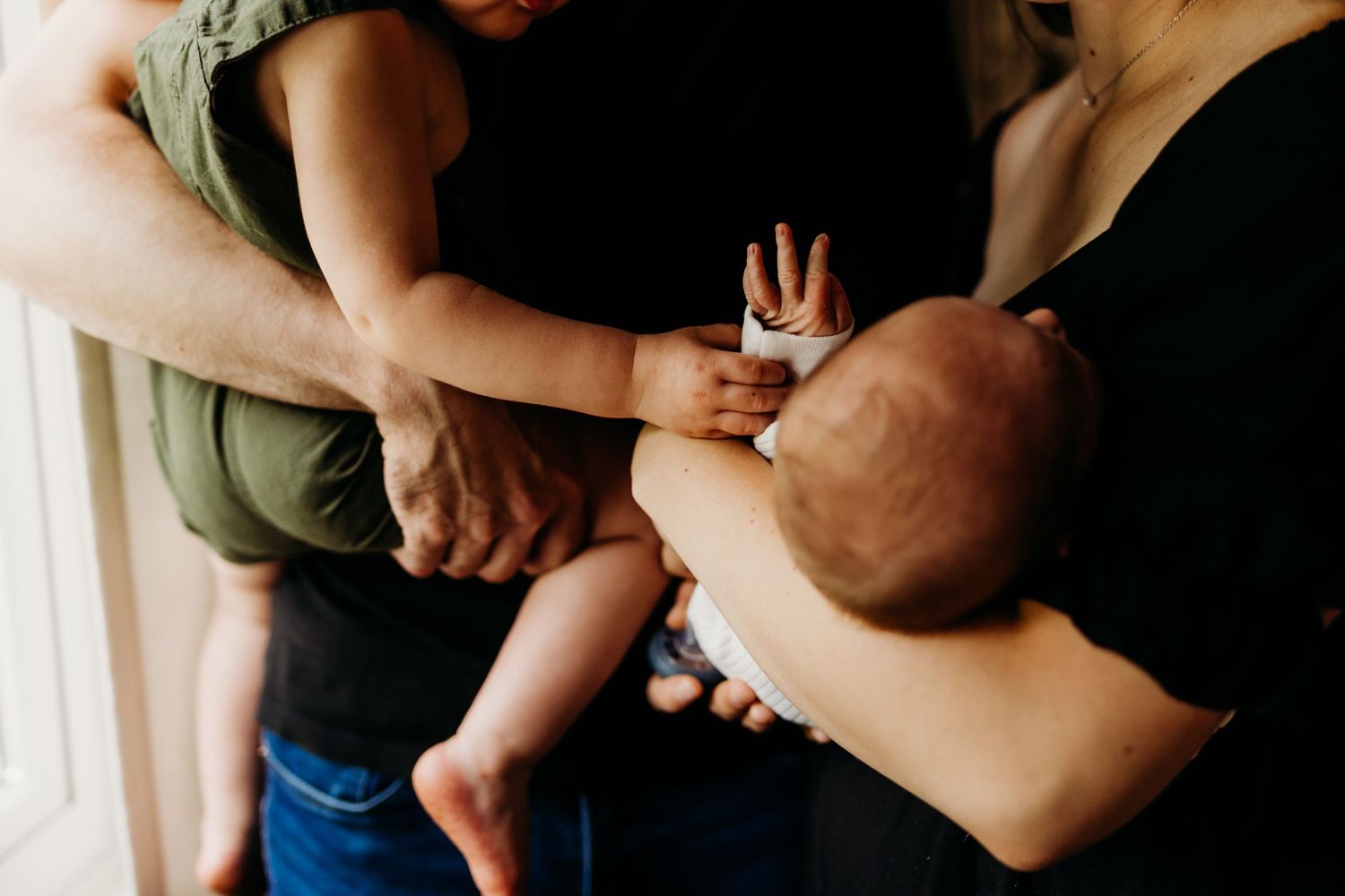 Parents holding and interacting with their baby in casual intimate setting.