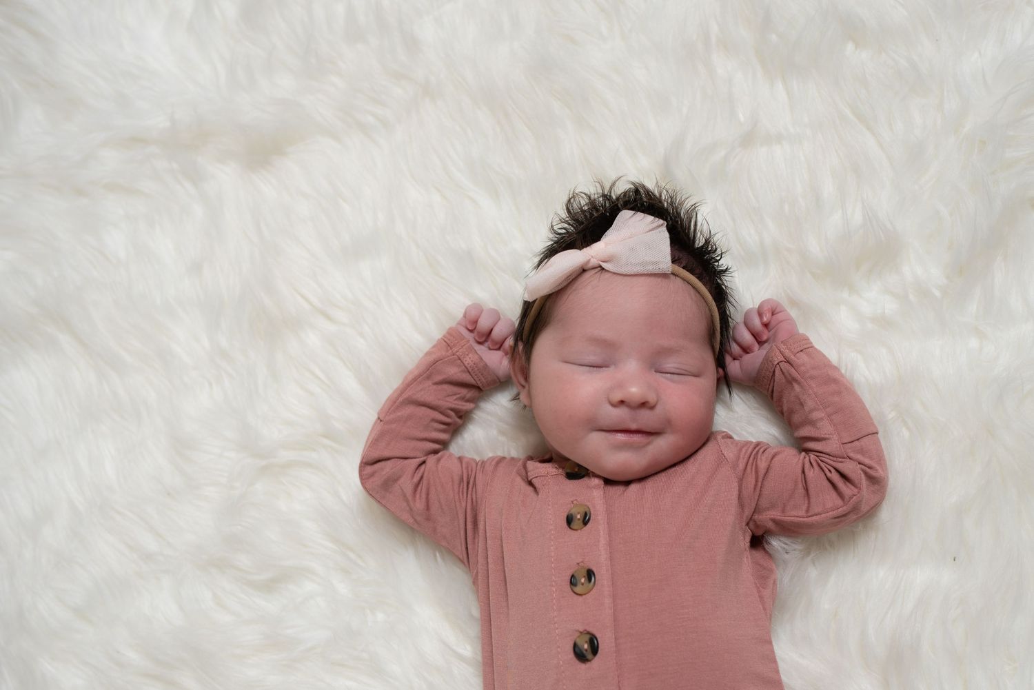 Newborn baby wearing pink outfit sleeping peacefully.