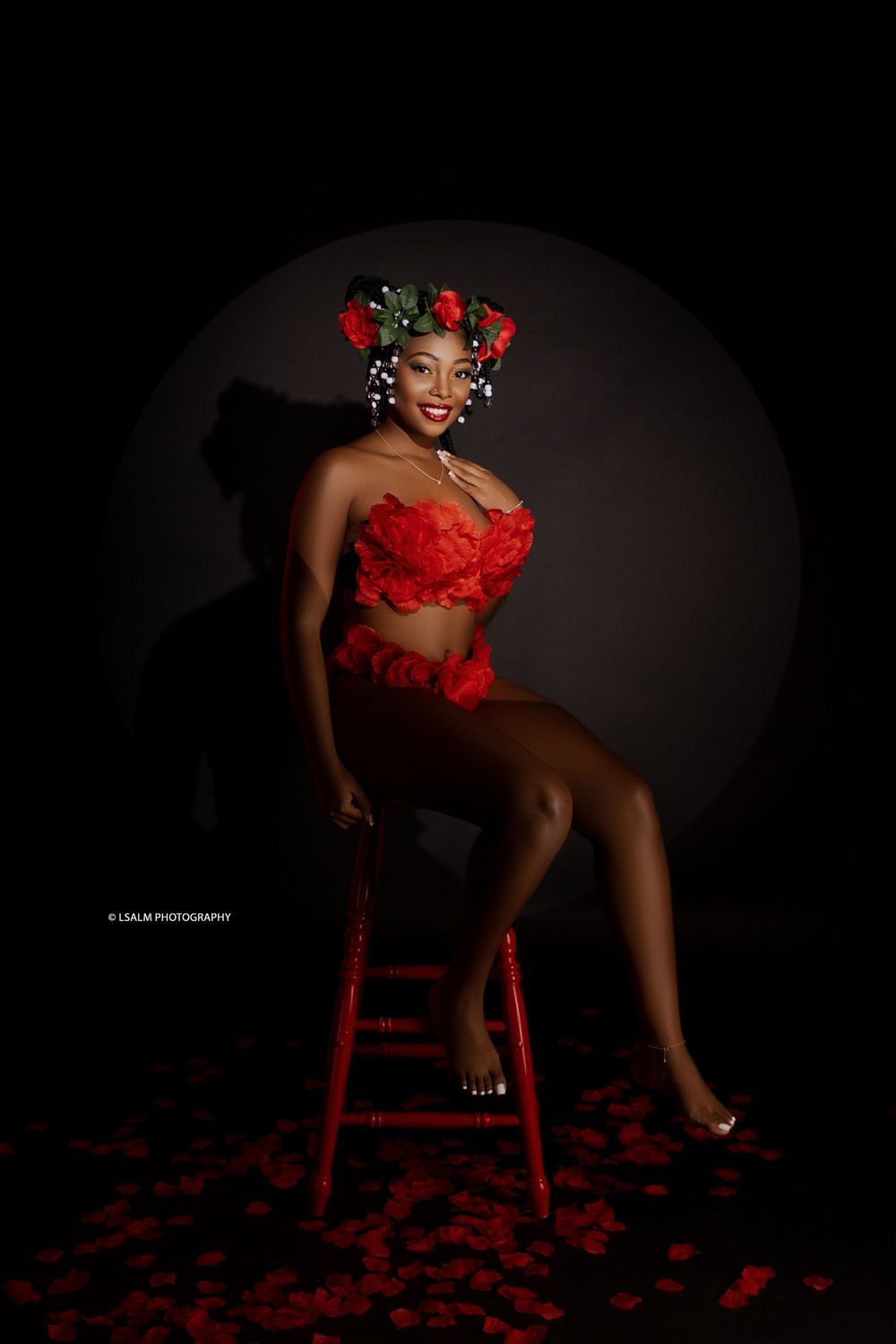 Glamour portrait featuring red lingerie and floral hair accessories in moody lighting.