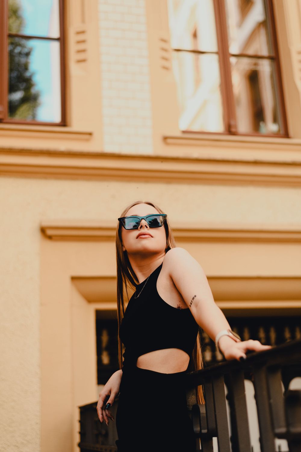Fashion portrait against peach-colored building wall in sunlight.