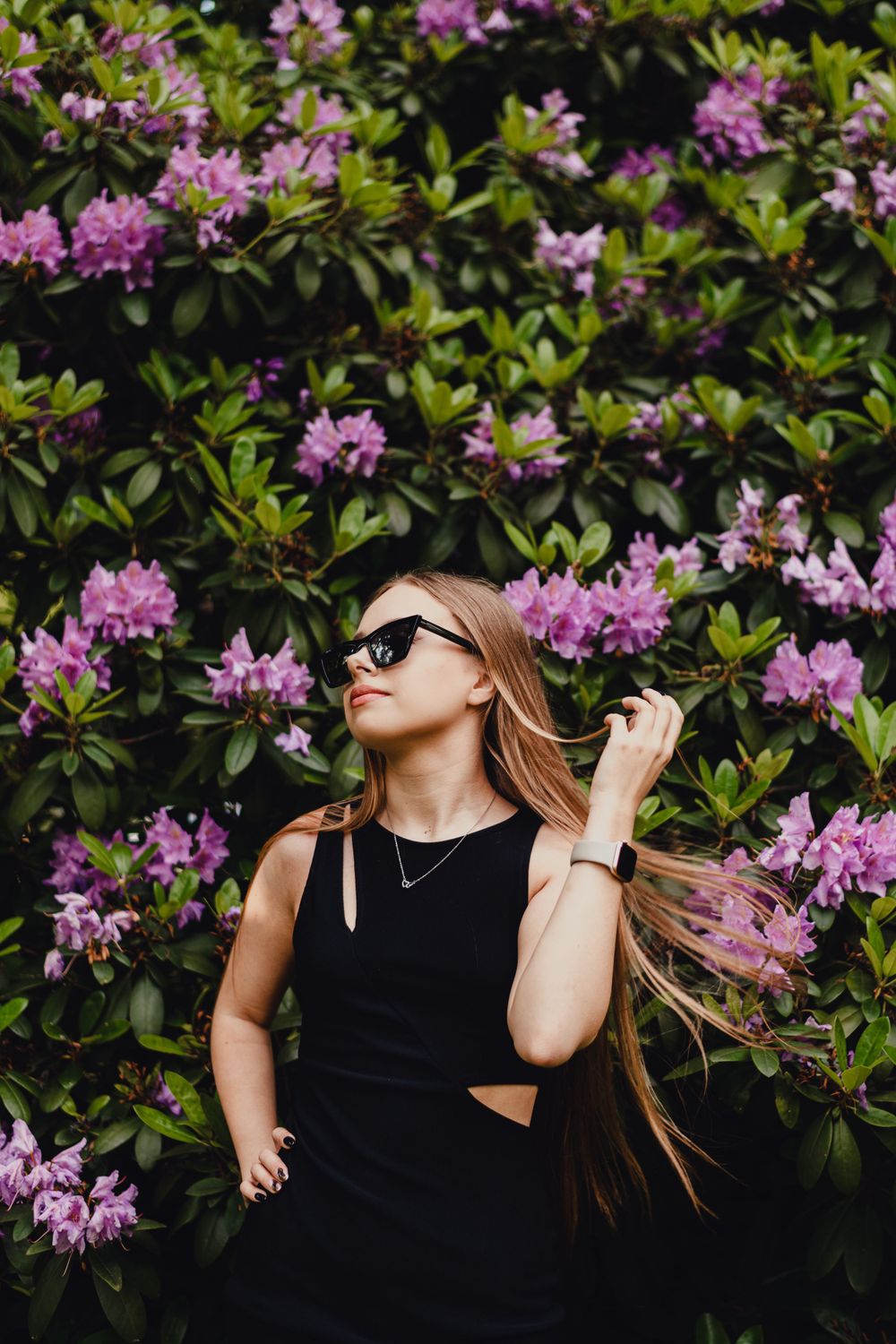 Fashion portrait with pink rhododendron flowers and sunglasses.