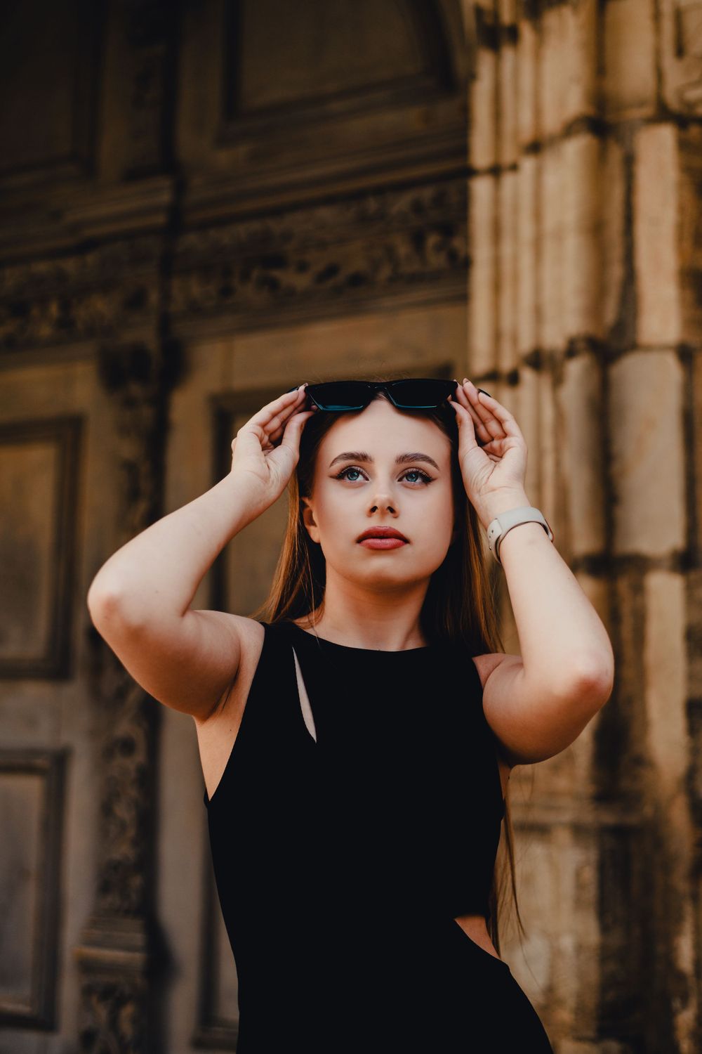 Artistic portrait against architectural columns in dramatic lighting.