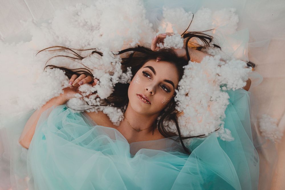 Ethereal portrait with turquoise fabric and smoke effects creating dreamy atmosphere.