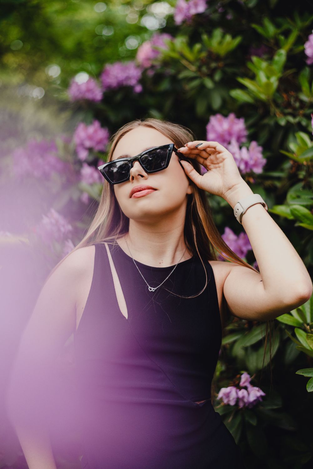 Artistic portrait with purple flowers and sunglasses in soft focus.