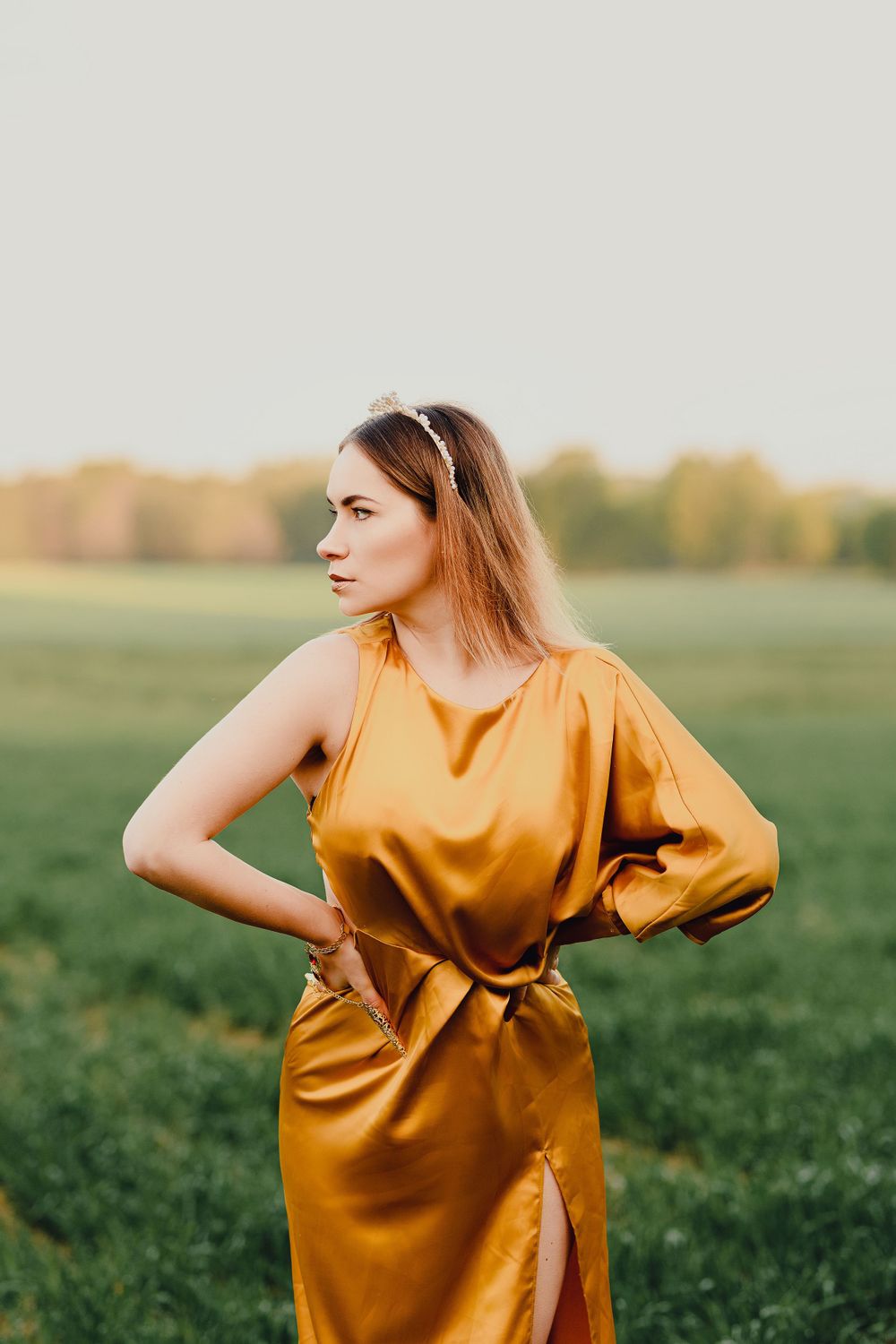 Elegant outdoor fashion photo featuring a flowing mustard yellow dress in a meadow setting.