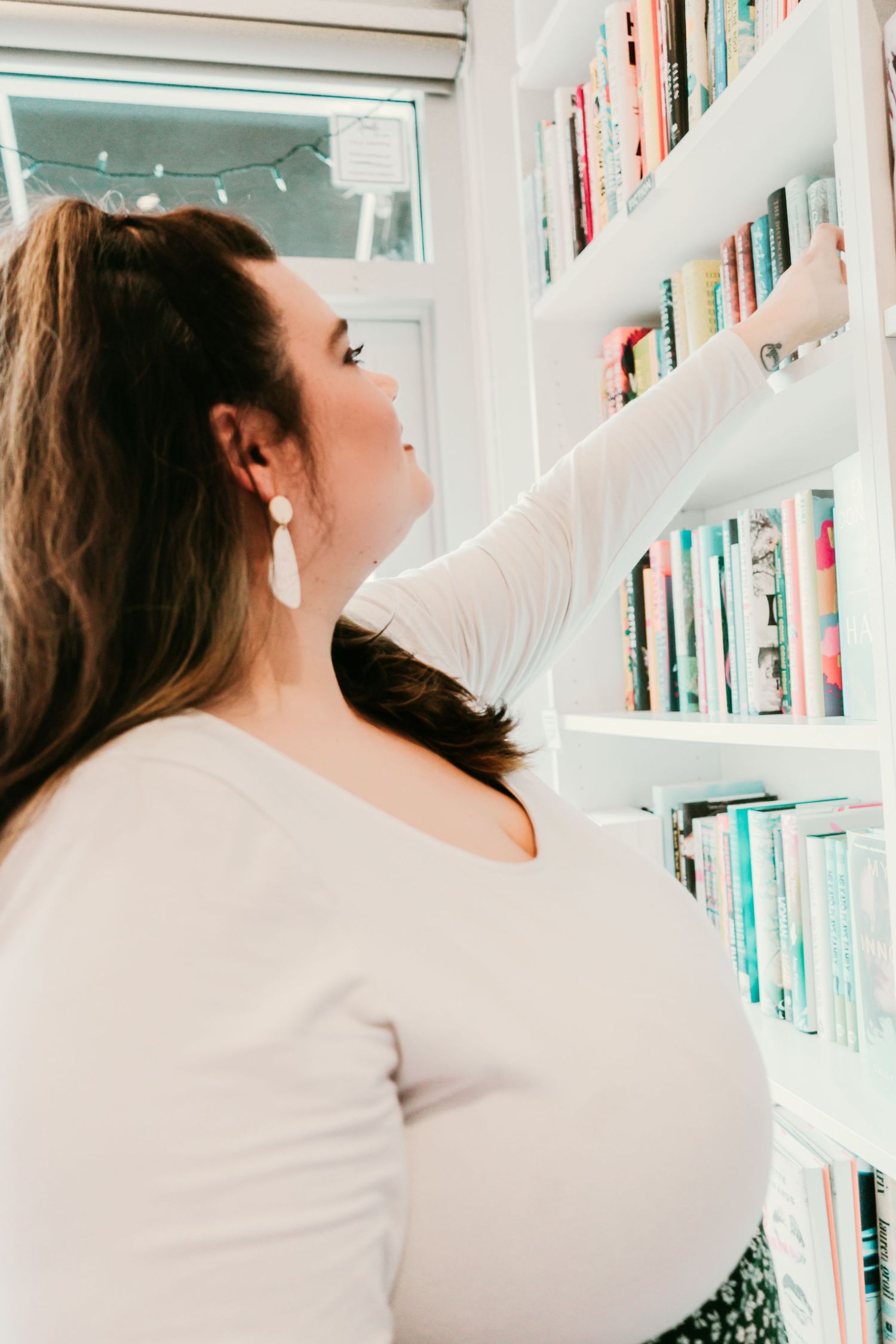 Outdoor Headshot Session in St. Pete, FL; Woman reaching for book on a shelf