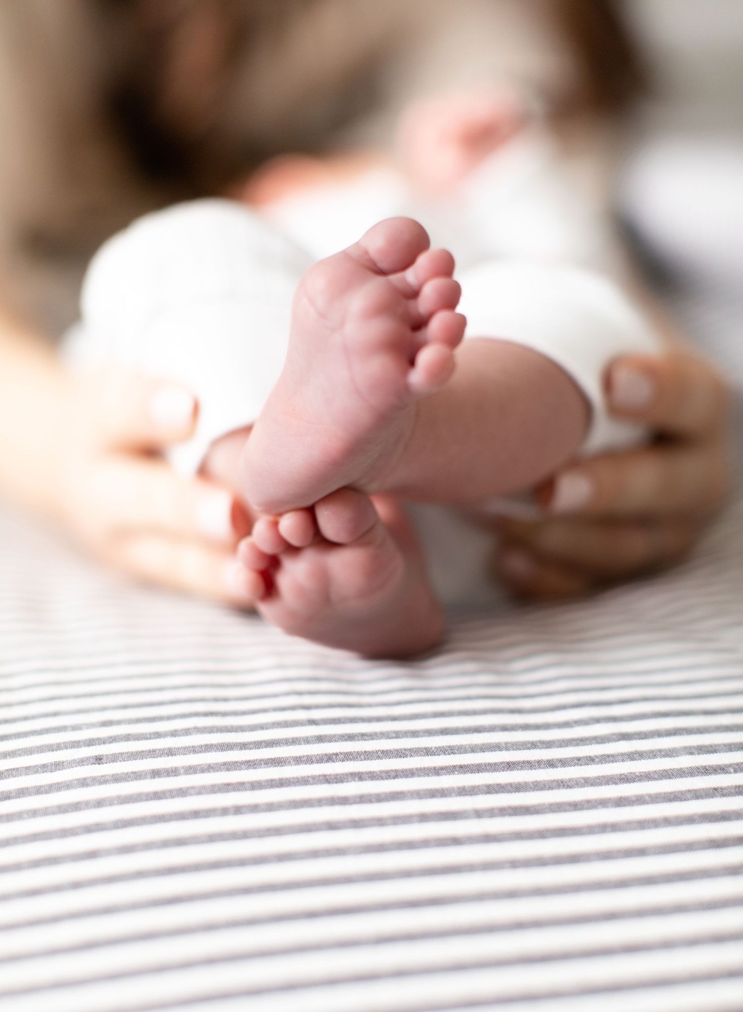 Close-up of tiny baby feet resting on striped fabric.