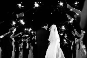 Wedding party holds sparklers creating magical light trails in the dark.