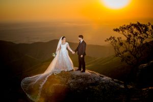 Golden sunset illuminates couple on clifftop for dramatic wedding portraits.