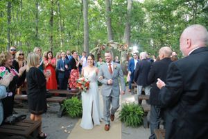 Joyful wedding recessional through outdoor garden pathway with guests celebrating.