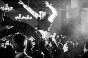 Black and white photo of energetic dance celebration at wedding reception.