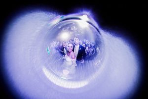 An artistic wedding photo captured through a spherical lens with a blue ethereal glow.