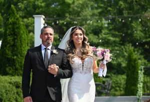 Traditional wedding processional in lush garden setting with string lights.
