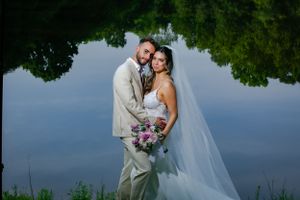 Newlyweds share intimate moments against scenic waterfront backdrop.