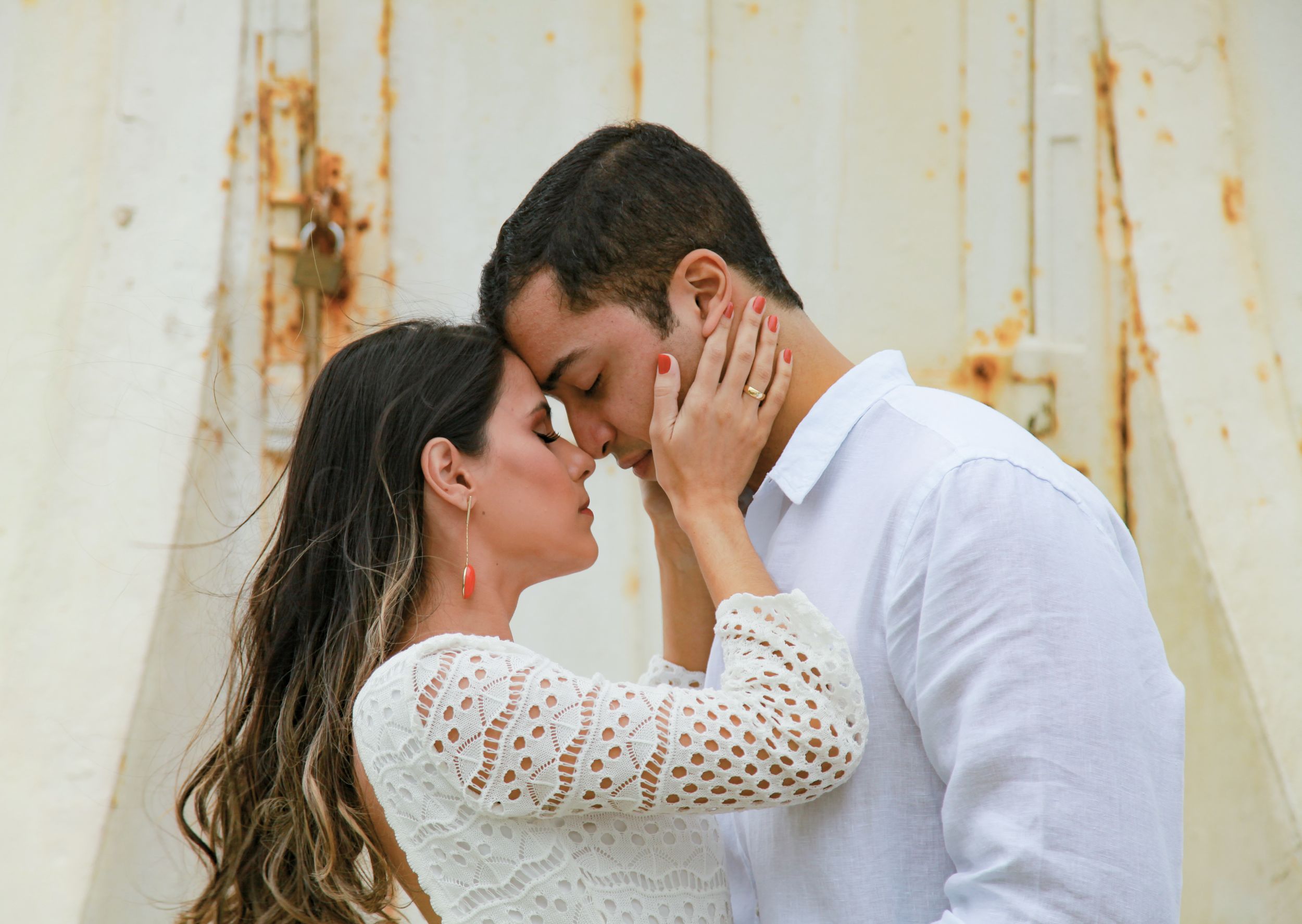 Romantic moment captured against rustic white weathered wall background.