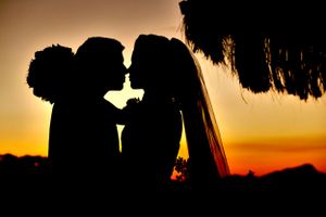 Silhouettes against a vibrant orange sunset create a romantic scene.