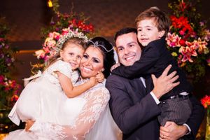 Wedding party group poses together with red floral decorations at evening reception.
