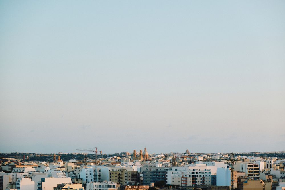 Panoramic cityscape view of Malta with church domes and buildings during dusk.