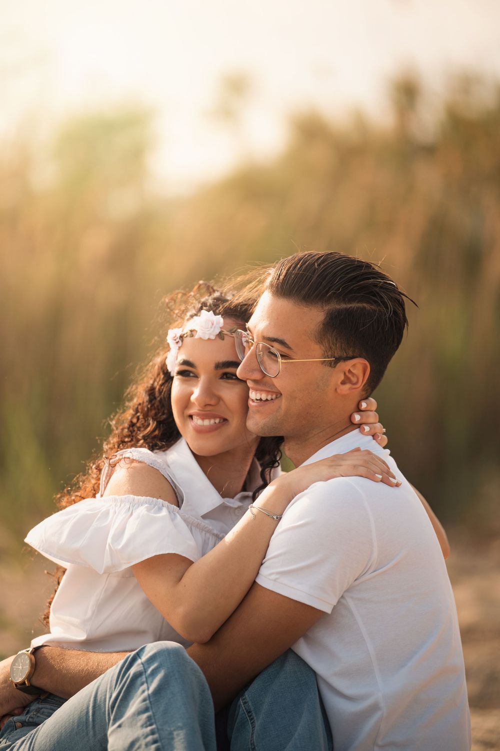 Couple in white clothing sharing intimate moment outdoors during sunset.