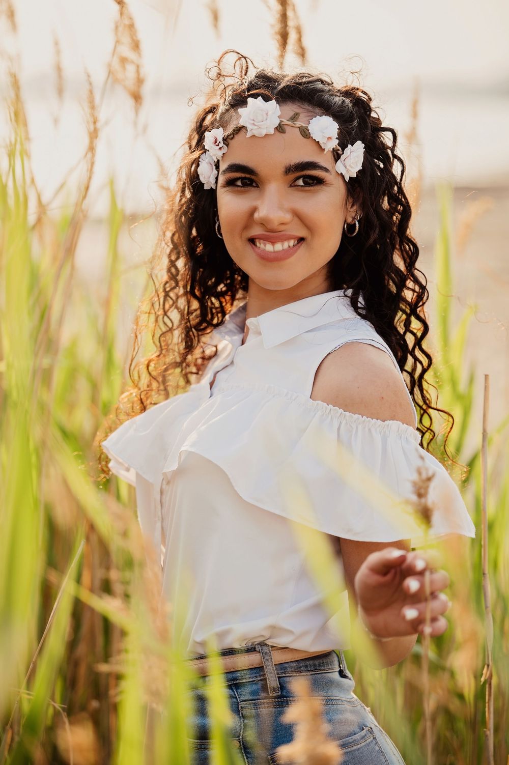 A carefree summer portrait with white floral crown and off-shoulder top among swaying beach grass.