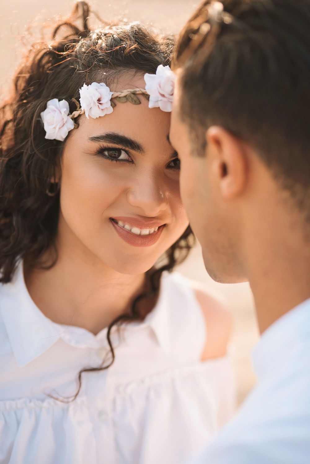 Close up of couple in white clothing sharing intimate moment outdoors.