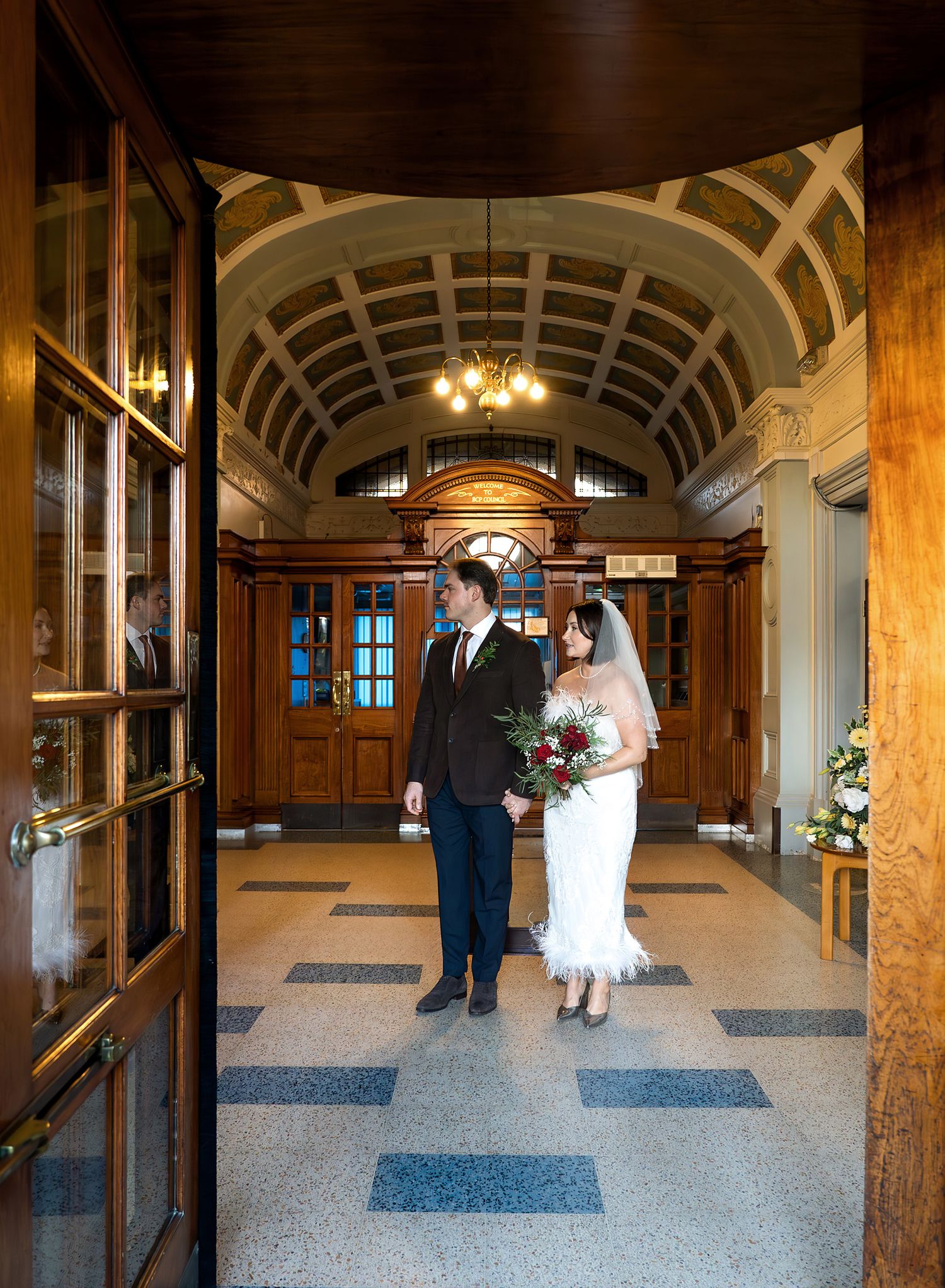 Reflection of bride and groom walking out of the Bournemouth registry wedding office.