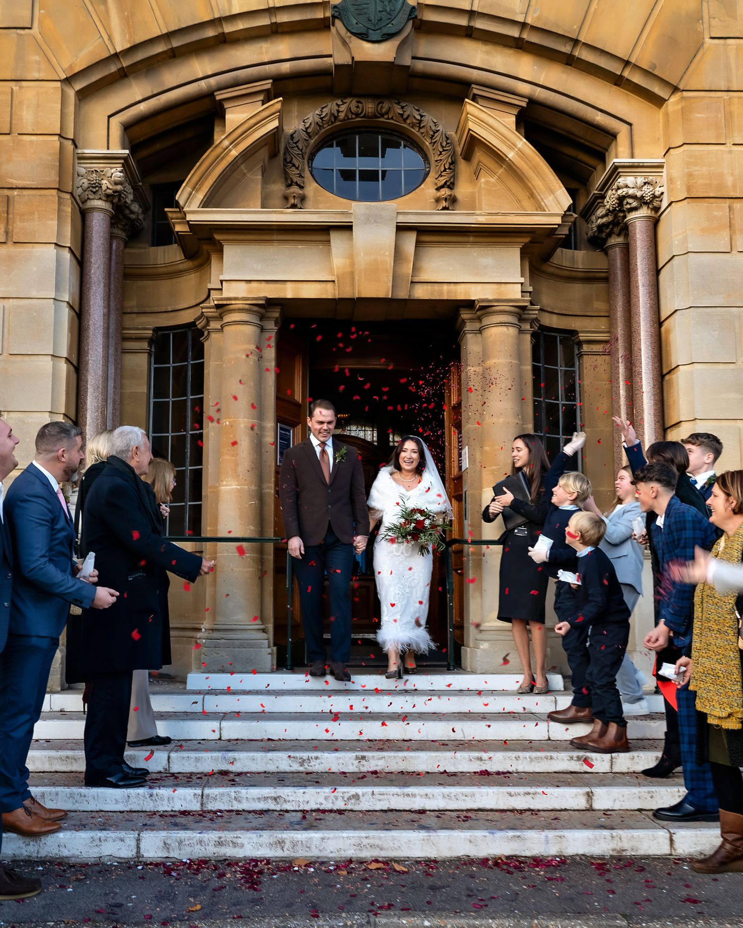 Bride and groom on stairs, guests throwing confetti on them. Location: Bournemouth.