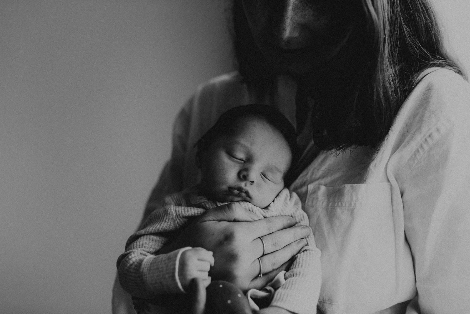 Black and white photo of sleeping newborn being cradled gently.