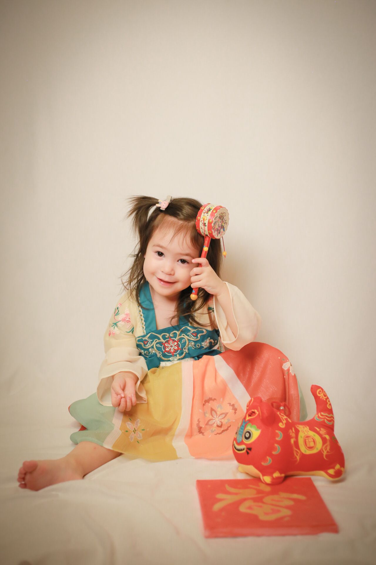 Child in colorful dress posing with Chinese New Year decorations and red envelopes.