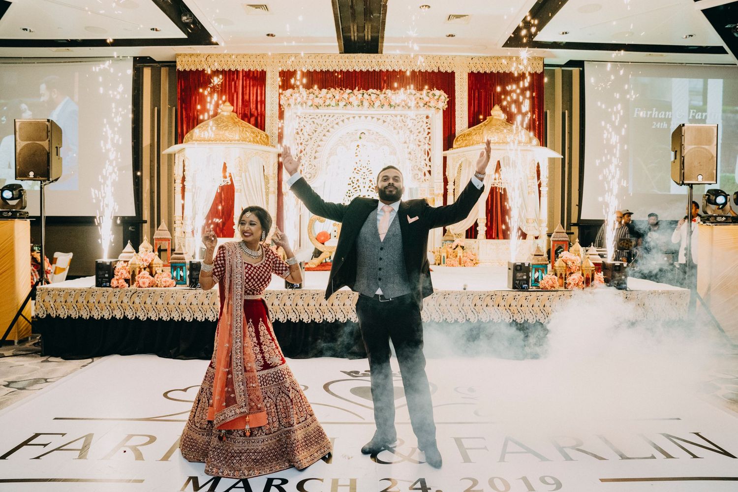 Wedding party members dancing energetically at a formal reception venue.