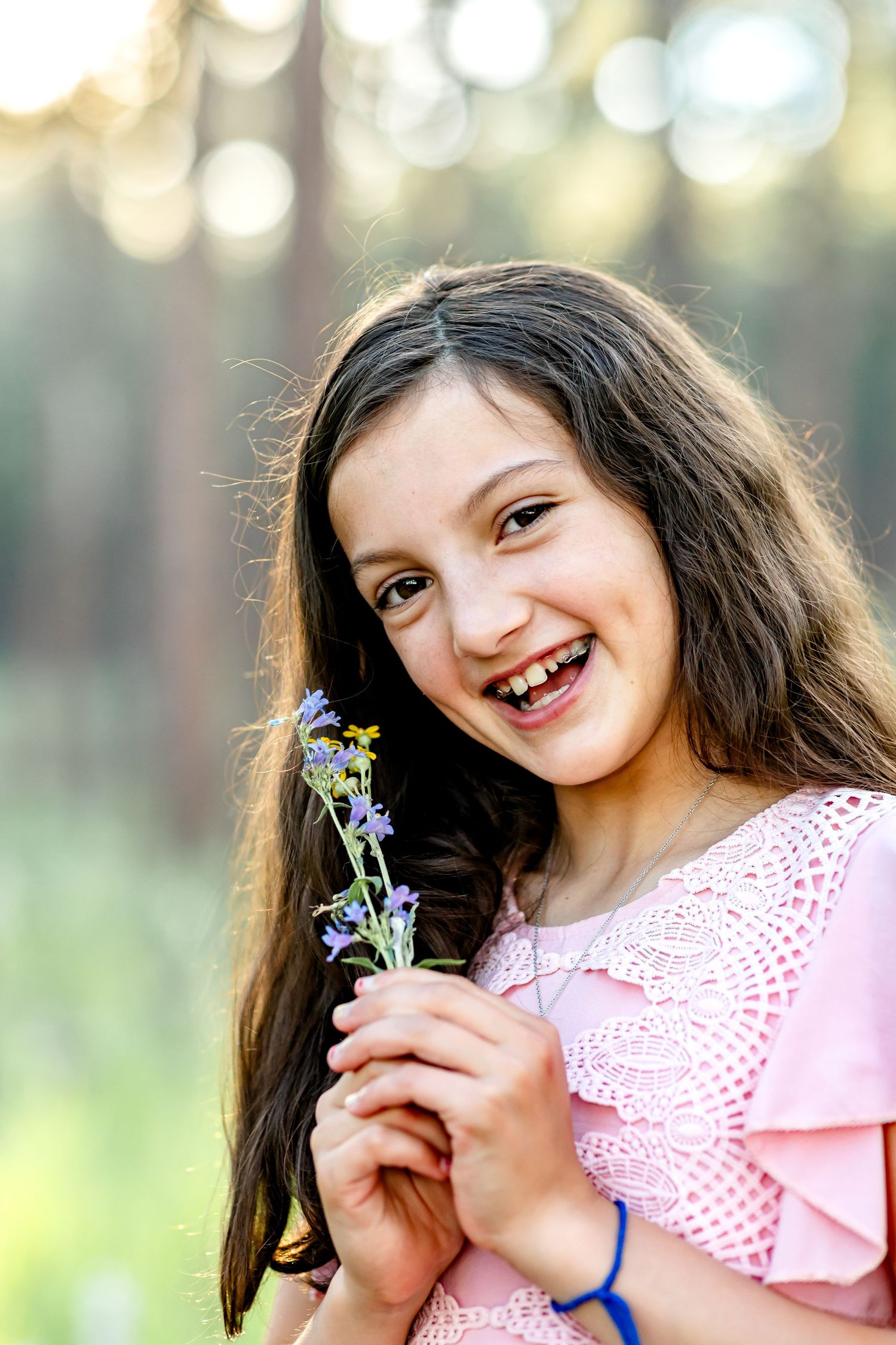 Young girl holds a wildflower and smiles during their family session in Colorado Springs.