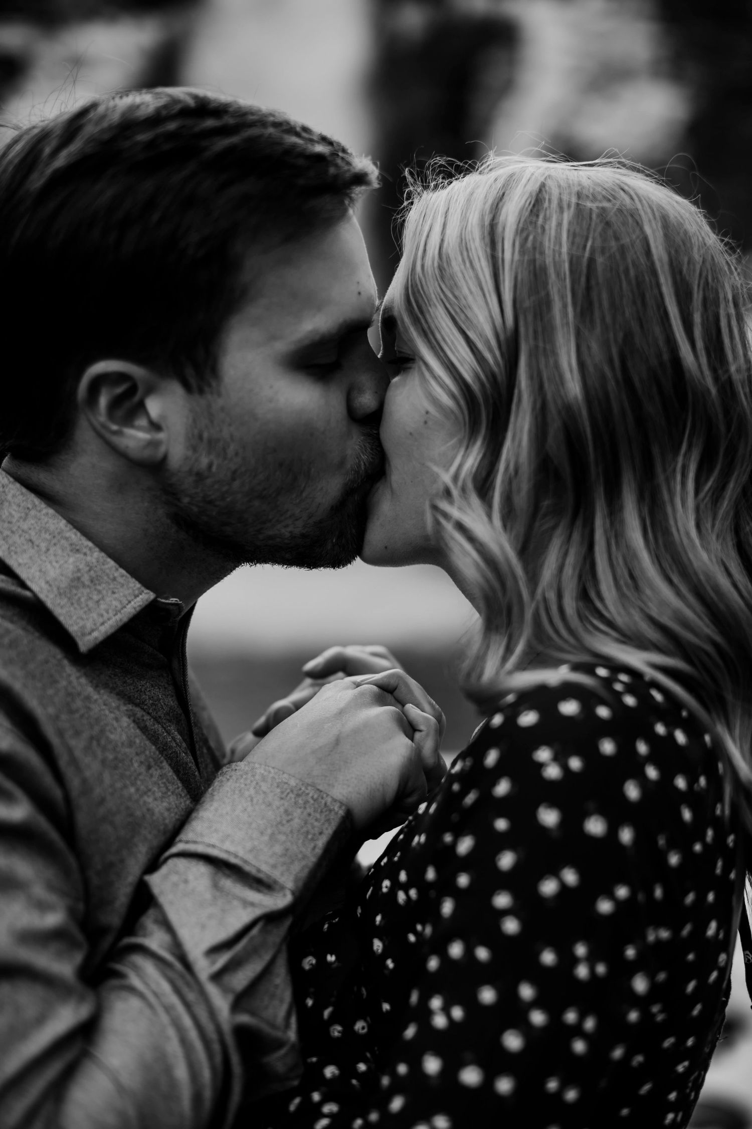 An intimate black and white portrait of a couple sharing a passionate kiss.