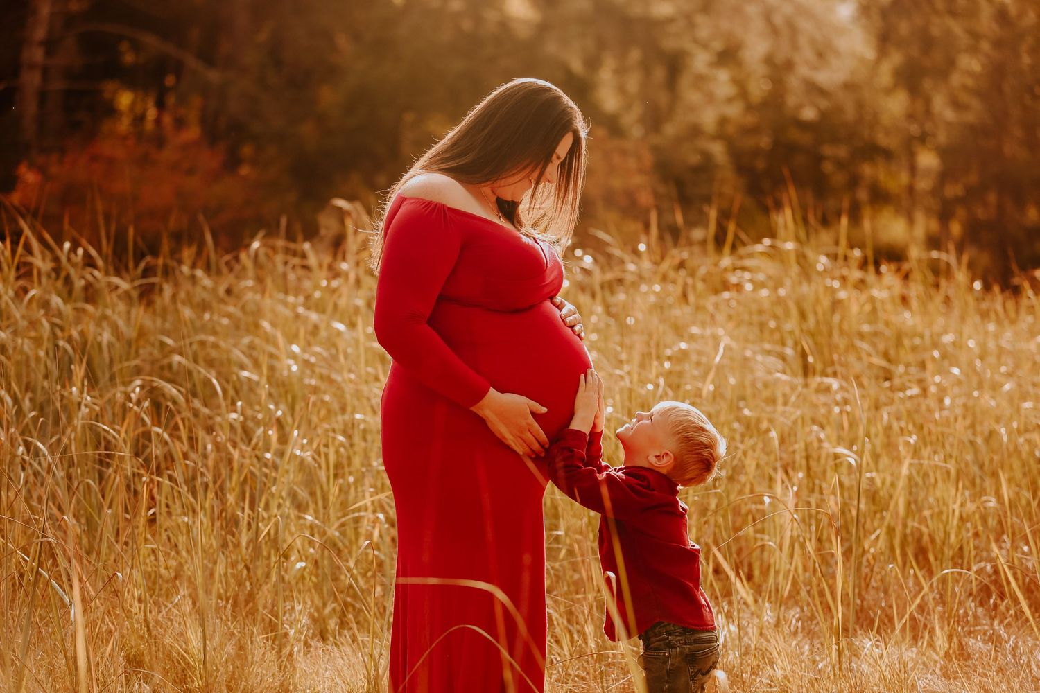 A mother and child share a tender moment in a sunlit field of tall golden grass.