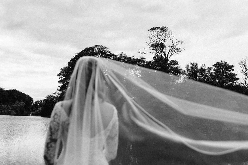Wedding veil flowing dramatically in the wind during outdoor portrait session.