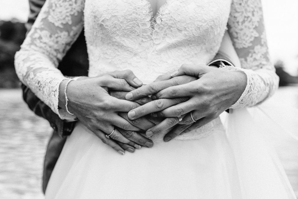 Close-up detail shots of hands and wedding dress lace details in black and white.