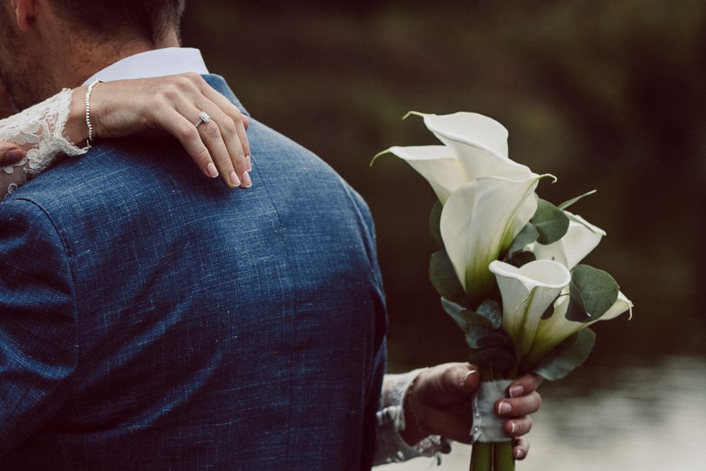 Wedding couple holding elegant white calla lily bouquet.