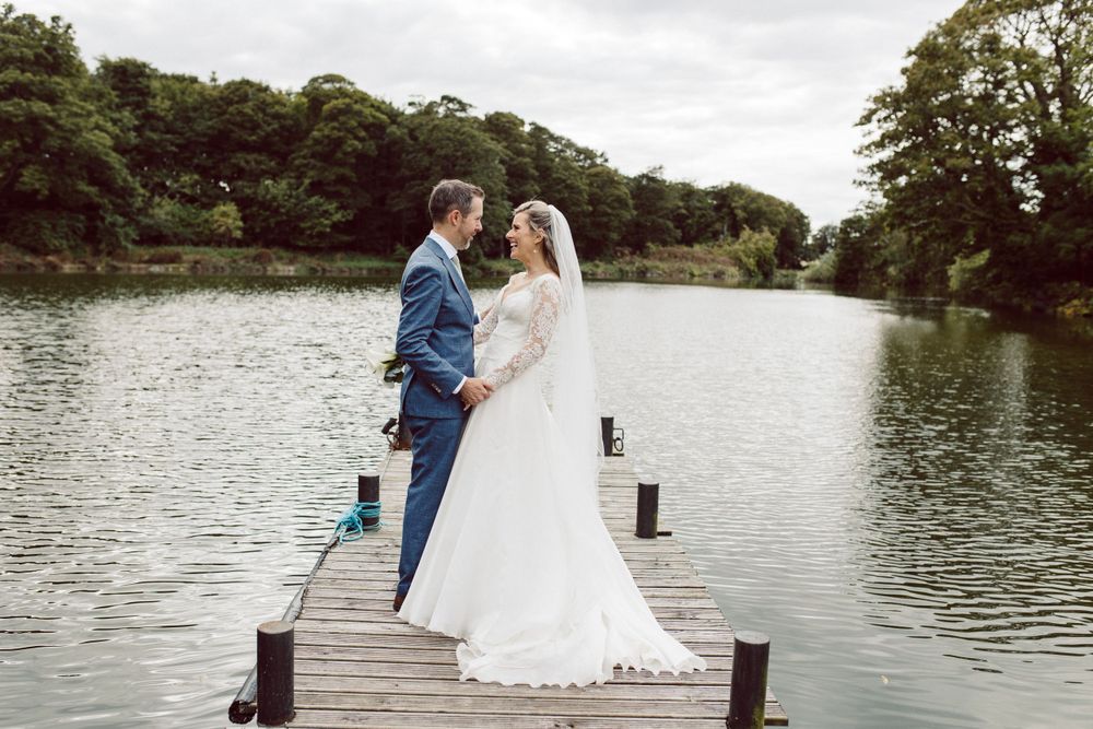 Couple sharing romantic moment on wooden dock overlooking serene lake.