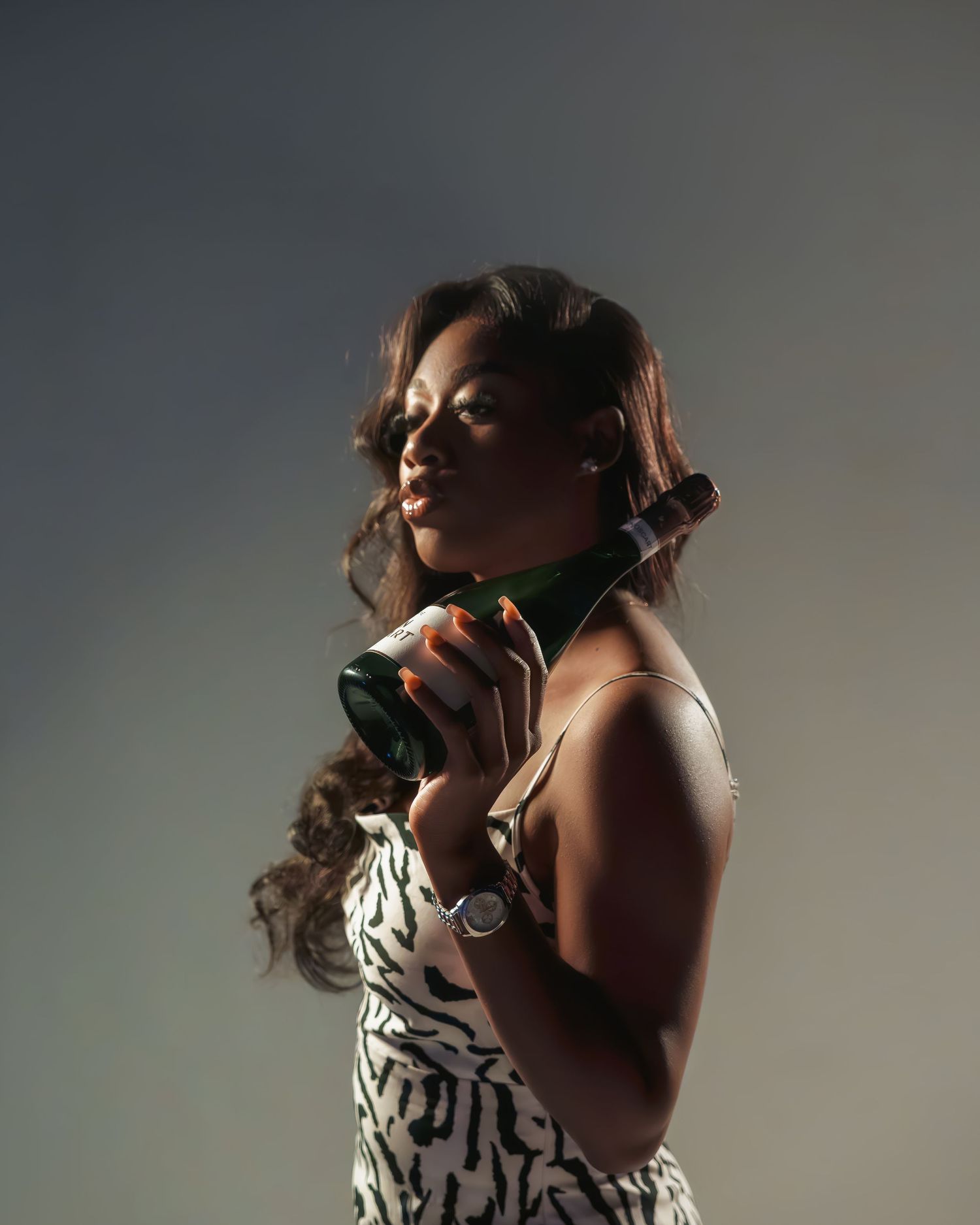 Artistic portrait with dramatic lighting holding champagne bottle.