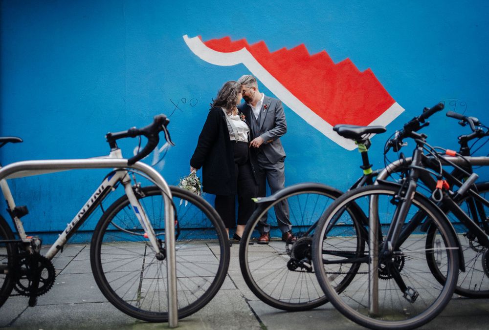 A romantic moment captured between bikes with a bright blue background and red art.