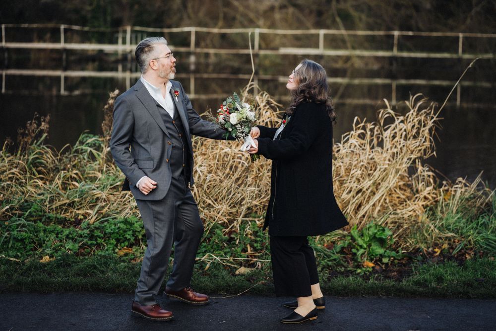 Two people share a lighthearted moment by a wooden fence in a rural setting.