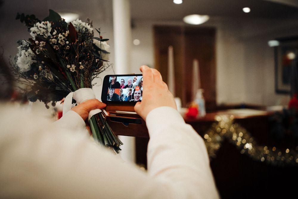 Someone takes a photo of a floral bouquet on a phone during an event.