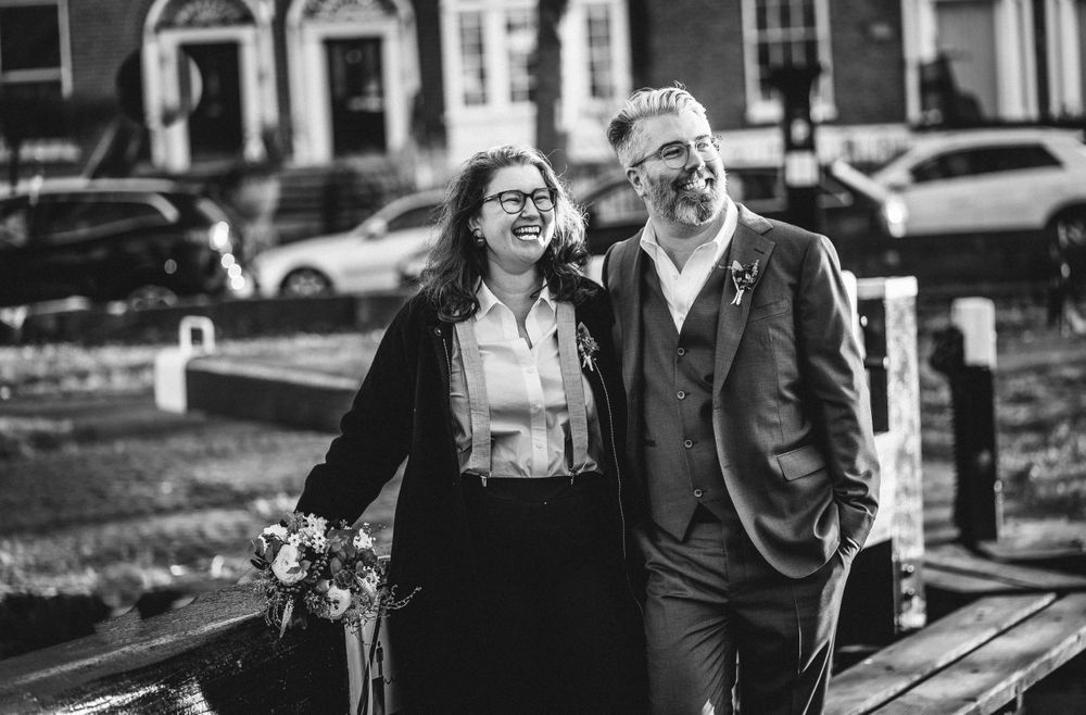 A couple shares a joyful moment together in black and white on a city street.