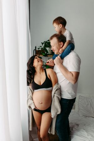 Intimate maternity lifestyle photo showing lovingly playful family moment in home setting.