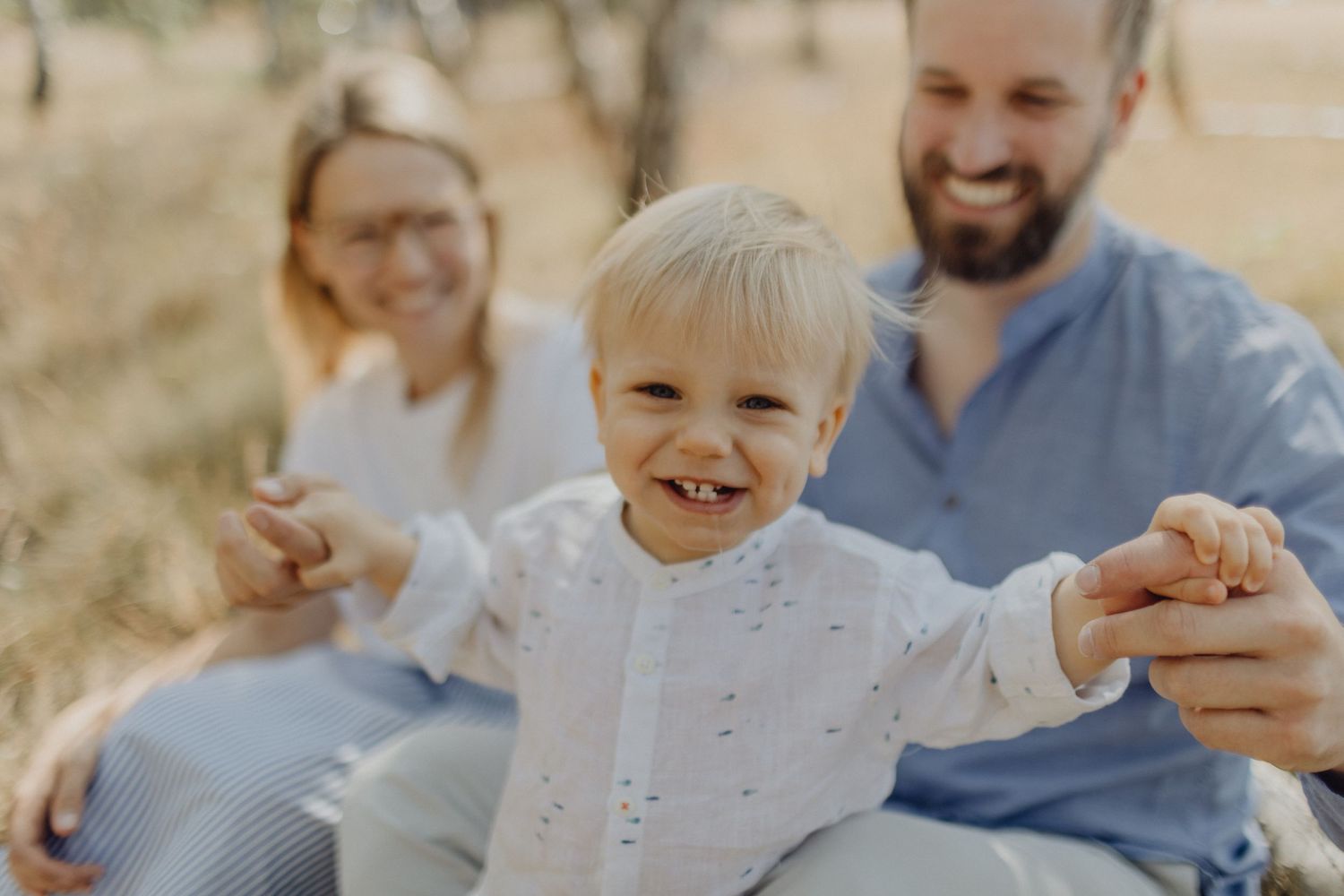 Joyful family moment captured in sun-drenched field.