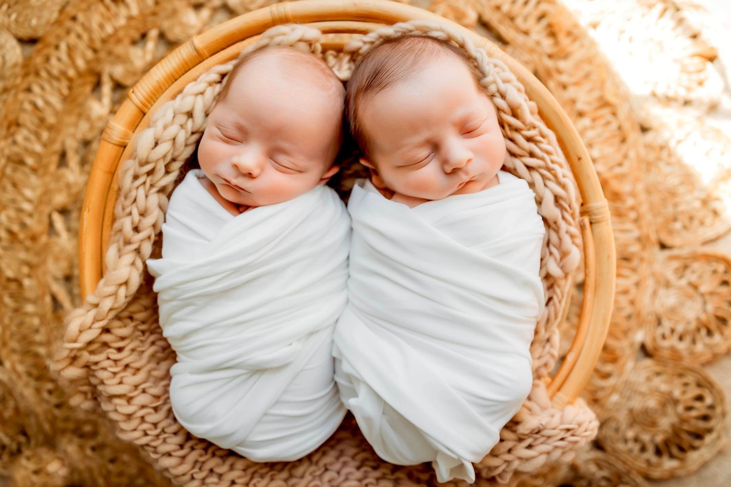 Two swaddled newborn twins sleeping peacefully together in a cozy blanket in Hamden, CT.