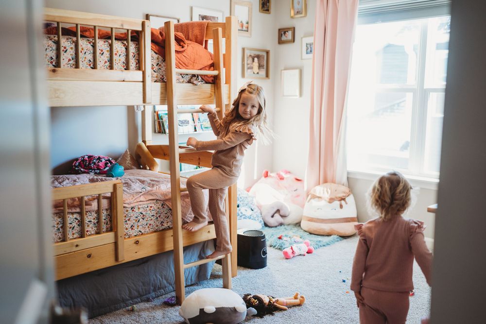 Children playing in a cozy bedroom with wooden bunk beds and natural lighting.