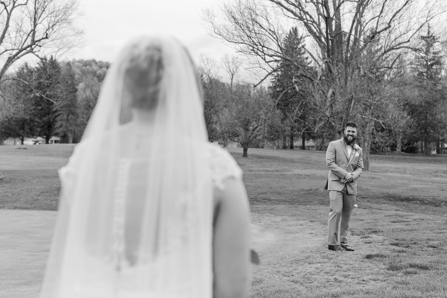 Wedding first look moment photographed from a distance in a scenic park.